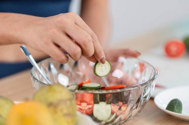Canlı bir salata yapmak için salatalık doğrayan, sağlıklı beslenme ve sürdürülebilirliği ön plana çıkaran bir kadının yakın çekimi..