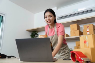 Girişimci çevrimiçi küçük işletmelerini yönetirken gülümseyerek lojistik ve müşteri hizmetlerine modern bir yaklaşım sergiliyor.