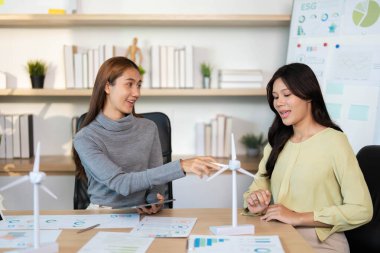 Yenilenebilir enerji projelerini tartışan, ESG girişimleri ve takım çalışmalarını vurgulayan meşgul profesyoneller.