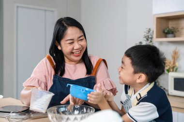 Mutlu bir anne ve oğlu yemek pişirme aktivitesine katılıyor, eğlenceli bir yemek pişirme seansı için malzemelerini ölçerken gülüşlerini paylaşıyorlar..