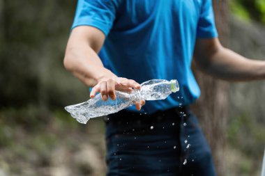 Bir gönüllü plastik şişeden su sallayarak çevreyi temizleme çabalarına aktif bir katılım gösteriyor..