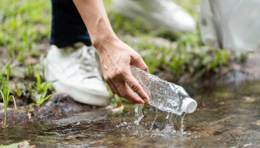 Kendini adamış bir gönüllü nehirden plastik bir şişe alıp çevresel sorumluluk ve sürdürülebilirliği teşvik ediyor..