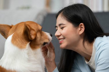 Bir kadın ve Corgi 'si sıcak ve davetkar bir ortamda birbirlerinin gözlerinin içine bakarak hassas bir anı paylaşıyorlar..
