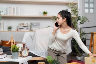 Bir kadın, kutuları ayarlarken, hareket sırasında birden fazla iş becerisini sergileyen bir telefon görüşmesi yapıyor..