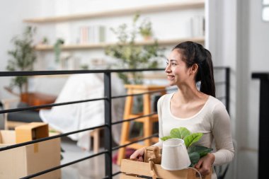 Bir kadın yeni evine özenle çiçek ve dekorasyon yerleştirir. Yeni bir başlangıç ve kişisel bir dokunuşu simgeler..
