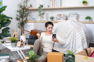 Genç bir kadın, kutular arasında başarılı bir hareketi kutlarken telefonuna bakarken sevinç ifade ediyor..