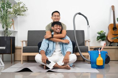 Ev ortamında temizlik, şefkat ve takım çalışması yaparken iki adam sıcak bir kucaklaşmayı paylaşıyor..