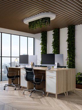 Modern masalar, bitkiler ve doğal ışığı davet eden büyük pencerelerin yer aldığı sürdürülebilir şık bir çalışma alanı.