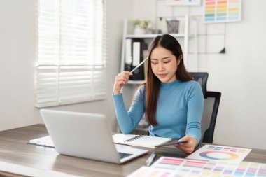 Parlak, minimalist bir ofiste, yaratıcı bir profesyonel tasarım projelerini değerlendirir, işbirlikçi bir ortamda odaklanma ve yenilik gösterir..