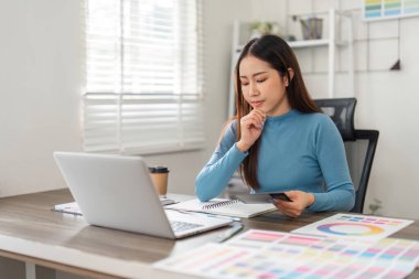 Huzurlu bir çalışma ortamında, bir tasarımcı derin düşüncelere dalmış, yaratıcı stratejisini geliştiriyor ve projeleri için sonraki adımları planlıyor..