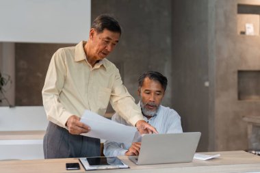 İşbirlikçi bir ortamda, iki deneyimli uzman iş dünyasındaki takım çalışması ve stratejik süreçleri vurgulayarak bir dizüstü bilgisayardaki verileri değerlendirir..