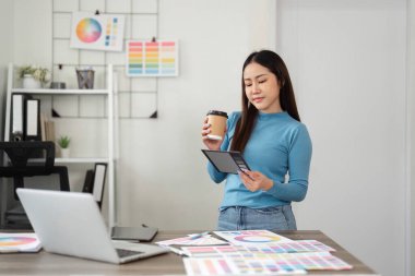 Düşünceli bir tasarımcı tabletindeki tasarım örneklerini gözden geçirir. Dijital öngörüleri yaratıcı bir ortamda kahve molası ile harmanlar..