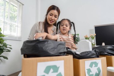 Bir anne kızını geri dönüşümleri ayırmaya çalışırken gülümser. Çevresel sorumluluk ve özen değerleri aşılar..