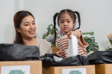 Şefkatli bir anne kızına geri dönüşümlü nesneleri nasıl ayıracağını gösterir, rahat bir yaşam alanında erken çevresel farkındalığı artırır..