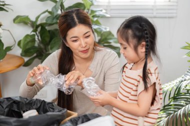 Bir anne kızına atık maddelerin geri dönüşümünü öğretiyor, sürdürülebilirliğin ve çevresel bakımın önemini vurguluyor.
