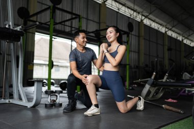 Kişisel antrenör, spor yaparken genç bir kadına destek ve motivasyonu vurgulayarak rehberlik eder..