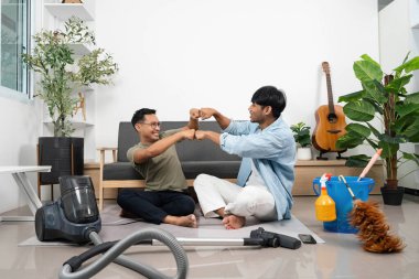 İki arkadaş temizlik yaparken keyifli bir anı paylaşıyorlar, sıcak bir yuva ortamında neşeli bağlantılarını vurguluyorlar..