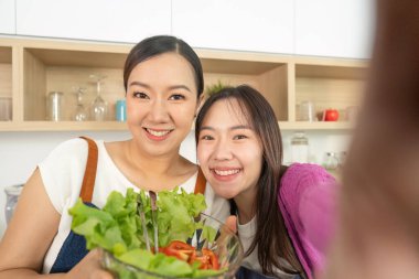 İki kadın bir kase taze salatayla selfie çekerken mutlu bir şekilde gülümsüyor. Sağlıklı beslenme ve arkadaşlığı kutluyorlar..