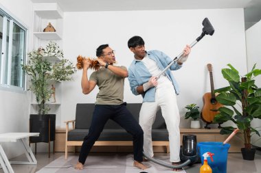 İki adam birlikte temizlik yaparken neşeli bir anı paylaşıyor. Ev işlerinde takım çalışması ve neşe sergiliyorlar..