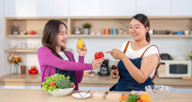 İki kadın, sağlıklı beslenme ve dostluğu vurgulayarak, taze ürünleri paylaşarak yemek hazırlıyor..
