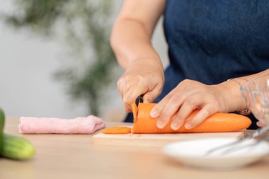 Modern bir mutfak atmosferinde havuç kesme, sağlıklı pişirme teknikleri sergileme odaklı bir fotoğraf..