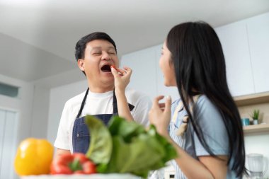 Neşeli bir çift mutfakta taze sebze hazırlar ve birlikte sağlıklı yemek pişirir..