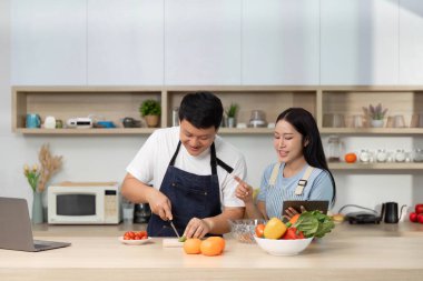 Bir çift yemek hazırlıyor, taze malzemeler kullanıyor ve şık bir mutfakta birlikte vakit geçiriyorlar..