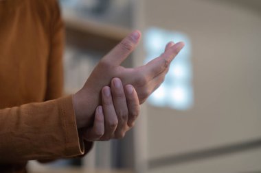 Bir insan nazikçe bileğini tutar, acı ya da rahatsızlık gösterir. Sağlık farkındalığına ve kişisel refahına odaklan.