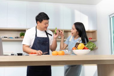 Bir çift, yemek pişirirken, aşklarını gösterirken ve modern mutfak ortamlarında iletişim kurarken neşeli bir anı paylaşıyor..