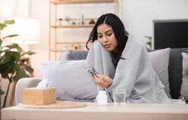 Rahatlatıcı bir çevreyle çevrili genç bir kadın kendini iyi hissetmezken evde oturup sağlığını düşünür..