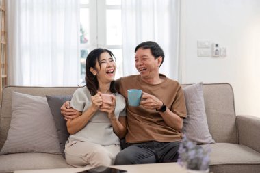 Yaşlı çift koltukta rahat rahat oturuyor, keyifli bir anı paylaşıyor ve evde boş vakitlerinin tadını çıkarıyorlar..