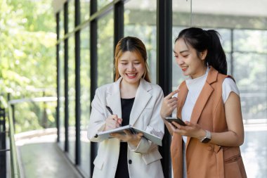 Modern bir ofis ortamında dijital cihazlar ve belgeler kullanarak işbirliği stratejilerini tartışan iki iş adamı.