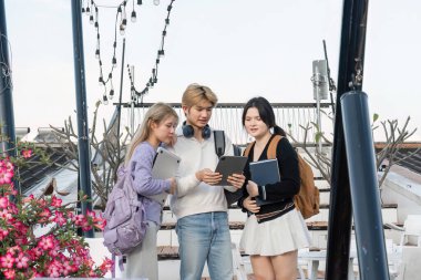Lise öğrencileri okuldan sonra birlikte çalışmak için toplanıyor, modern ortamlarda dizüstü bilgisayarlar ve kitaplarla birlikte öğrenme ve takım çalışmasını teşvik ediyorlar..