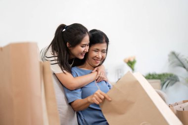 Neşeli bir anne ve çocuk alışveriş yaparken, kağıt poşetler tutarken ve evde gülümserken..