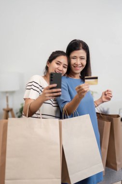 Mutlu bir anne ve çocuk, alışveriş sonrası kese kağıdı tutarken gülümsüyor, neşeli bir aile anını yakalıyor..