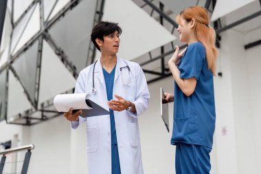 Bir erkek doktor ve asistanı çağdaş bir tıbbi ortamda hasta bakımını, takım çalışmasını ve profesyonelliği tartışırlar..