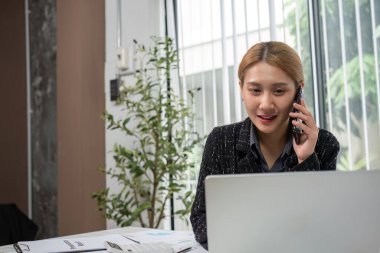 Ofisteki iş kadını dizüstü bilgisayardaki grafikleri analiz ediyor, stratejik planlama için finansal verilere odaklanıyor.