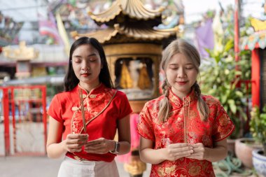 Geleneksel giyinmiş iki kadın canlı bir kültür mirasının simgesi olan Çin Yeni Yıl ritüeline katılıyorlar..