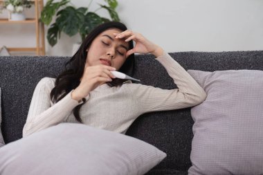 Kendini iyi hissetmeyen genç bir kadın evdeki hastalığın vücut bulmuş haliyle koltuğun termometresinde dinleniyor..