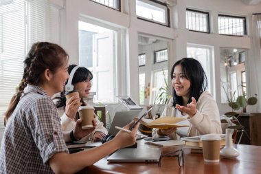 Ödevlerini birlikte yapan öğrenciler, parlak ve modern bir çalışma alanında fikirleri ve kaynakları paylaşıyorlar..