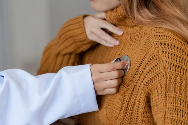 Bir doktor, bir hastaya sağlık kontrolü yapmak için steteskop kullanır, profesyonel sağlık ve sağlık hizmetlerinin altını çizer.