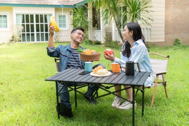 Bir çift canlı bir bahçede birlikte geçirdikleri zamanı kutlarken taze meyve ve hamur işlerinin keyfini çıkararak refah ve mutluluğu destekliyor..