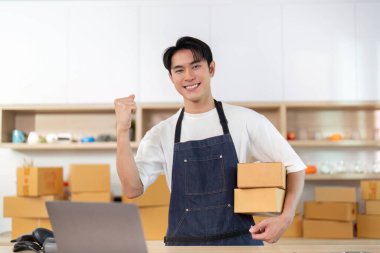 Genç bir girişimci, e-ticaret işini yönetirken sevinç ifadesi sergiliyor..