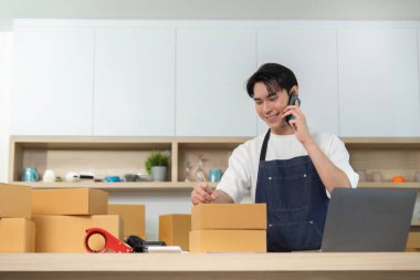 Paketleri düzenlerken, müşteri desteği ve lojistik yönetimine dikkat çekerken, genç bir adam telefonda konuşur..