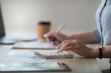 Ofisinde çalışırken verileri analiz etmek için hesap makinesi kullanan odaklanmış bir kadın..