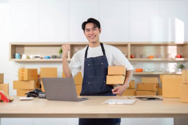 Genç bir girişimci, e-ticaret işini yönetirken sevinç ifadesi sergiliyor..