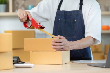 Bir çalışan kaseti dikkatlice kutulara yerleştirir ve onları iyi organize edilmiş bir e-ticaret ortamında nakliyeye hazırlar..