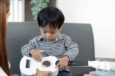 Genç bir çocuk annesinin yardımıyla oyuncak gitar çalarak müziği keşfediyor, yaratıcılığı ve öğrenmeyi teşvik ediyor..