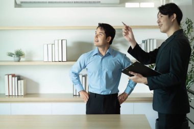 İki meslektaş, takım çalışması ve stratejik planlamayı vurgulayarak, projeleri hakkında verimli bir konuşma yapıyorlar..