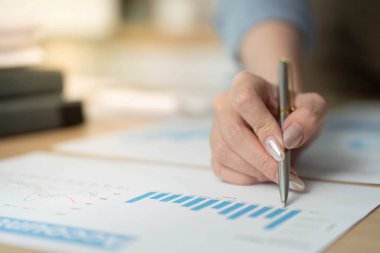 Profesyonel bir kadın finansal grafikleri analiz eder, iş hayatında veri odaklı karar vermenin önemini gözler önüne serer..